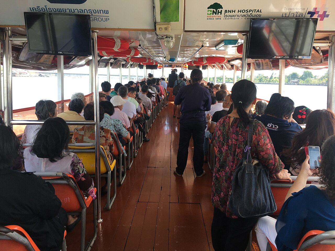 เรือด่วนเจ้าพระยาแล่นบนแม่น้ำผ่านวัดและตึกริมน้ำกรุงเทพ