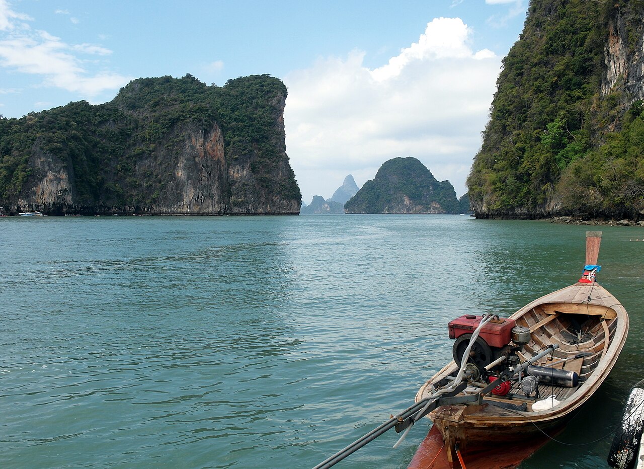 เกาะห้อง กระบี่ — เรือหางยาวลอยอยู่ในลากูนน้ำเขียวที่ล้อมด้วยหินผาปูนสูงทั้งสองข้าง
