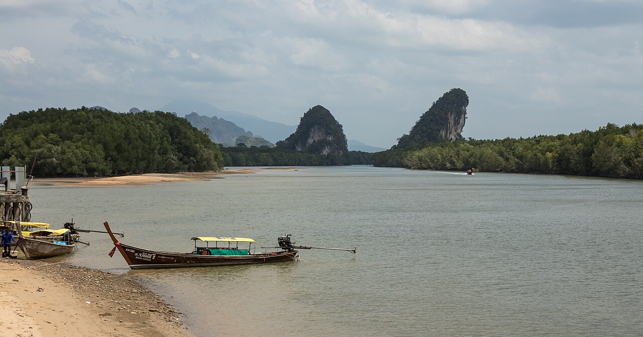 เขาขนาบน้ำ กระบี่ — เขาหินผาปูนคู่สองลูกขนาบแม่น้ำกระบี่ มีเรือหางยาวจอดริมตลิ่ง ป่าโกงกางสองฝั่ง