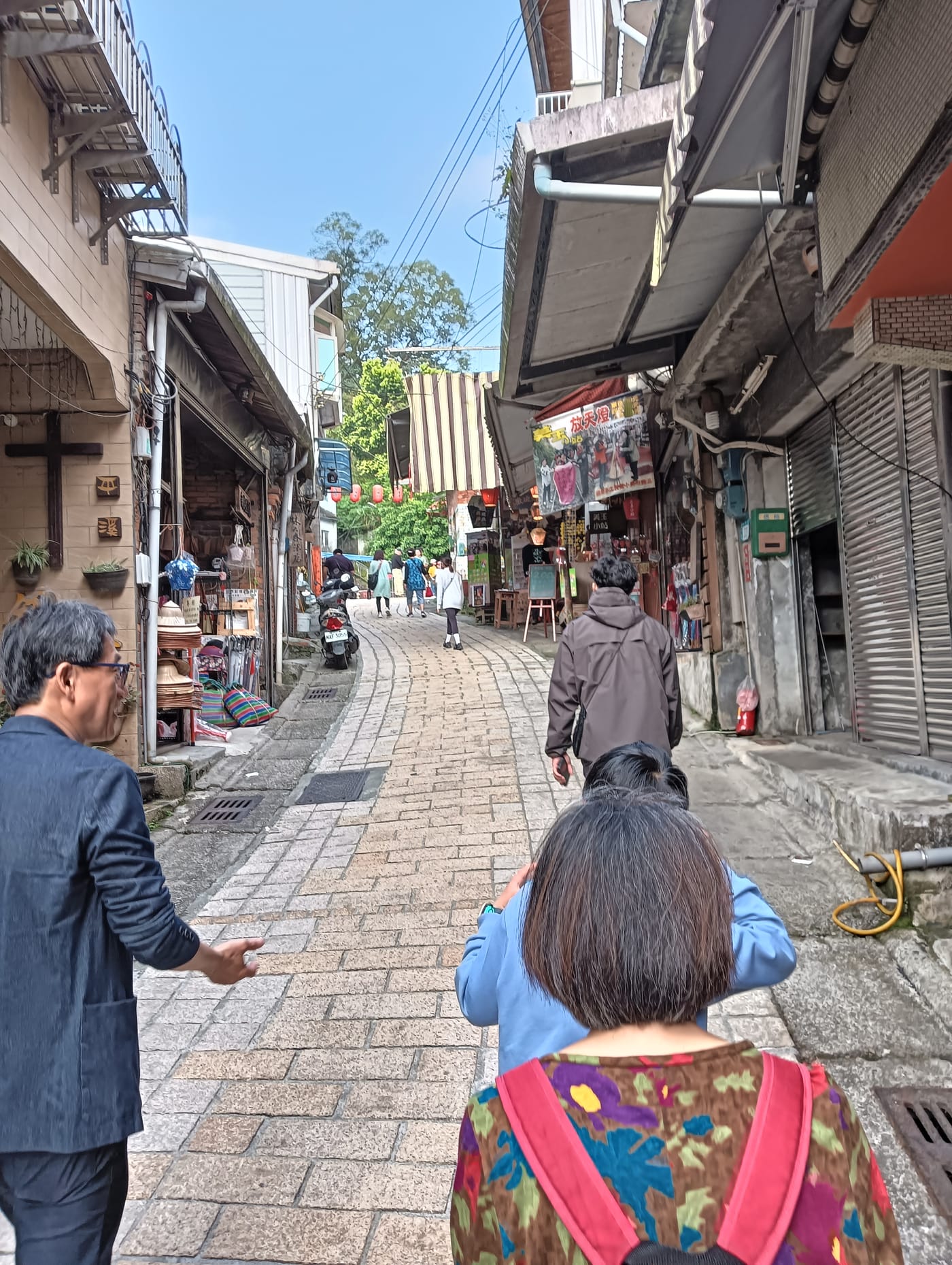 ถนนโบราณผิงซีบนเนินเขา มีบ้านเก่าสองข้างทางและนักท่องเที่ยวเดินบนทางเดินปูหิน ในเขตผิงซี นิวไทเป