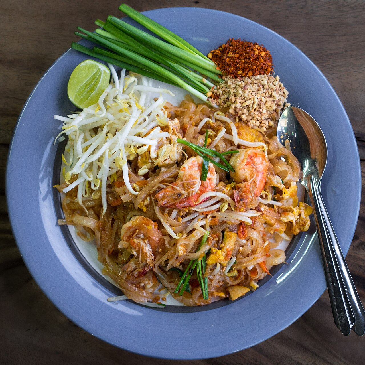 ผัดไทยกุ้งสด — เส้นจันท์ผัดสีส้มอมน้ำตาล โรยถั่วลิสงป่น เสิร์ฟพร้อมมะนาวและกุ้ง