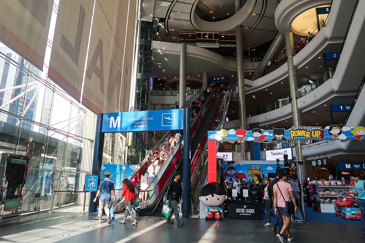 โถงกลาง Terminal 21 อโศก ห้างธีมสนามบินที่มีบันไดเลื่อนยาวและป้ายบอกชั้นแบบป้ายสนามบิน ชั้น 5 คือฟู้ดคอร์ท Pier 21