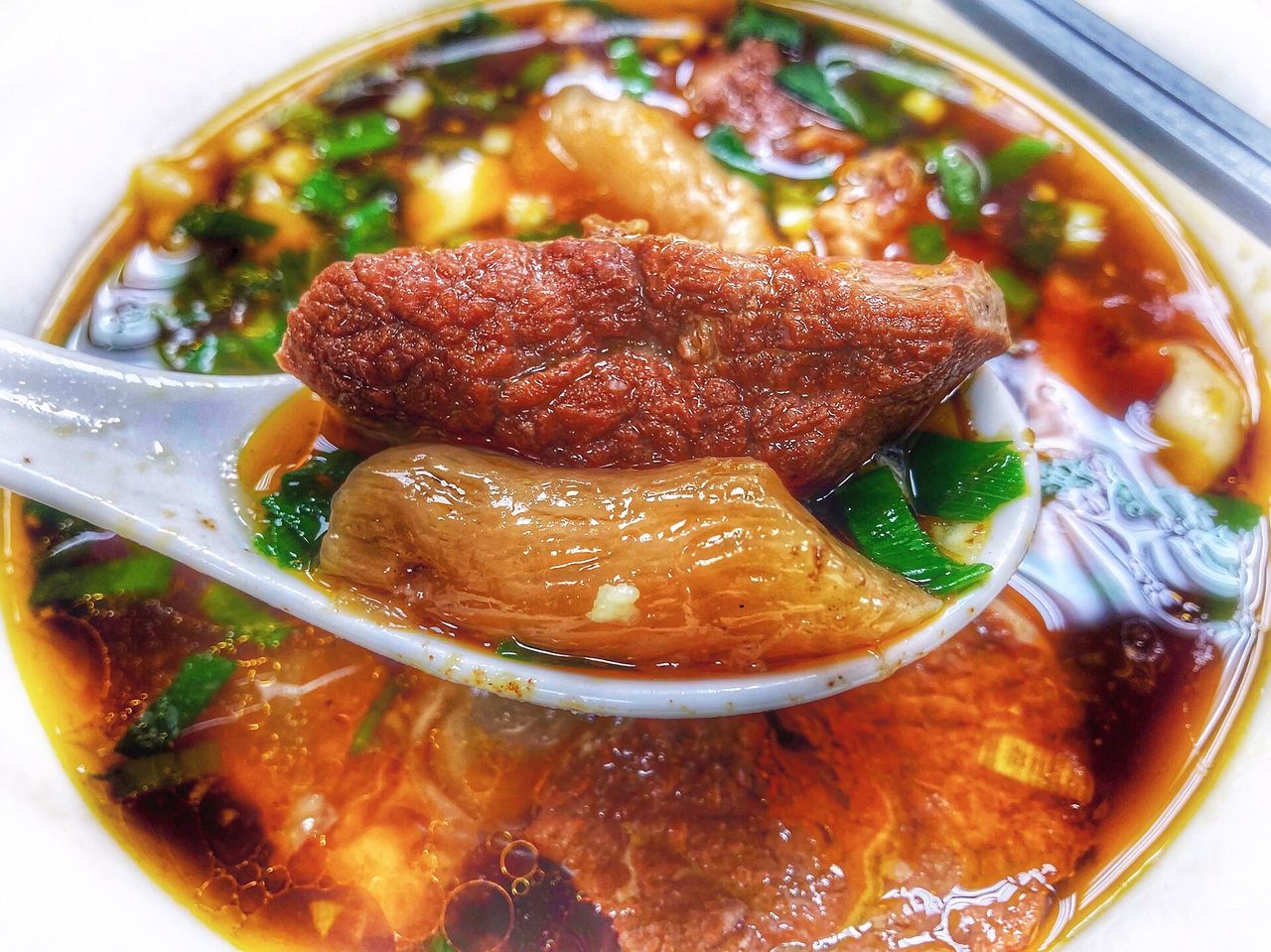 ก๋วยเตี๋ยวเนื้อน้ำซุปแดงหงเซาของไทเป ช้อนตักเอ็นเนื้อใสนุ่มและชิ้นเนื้อตุ๋นเปื่อย โรยต้นหอม