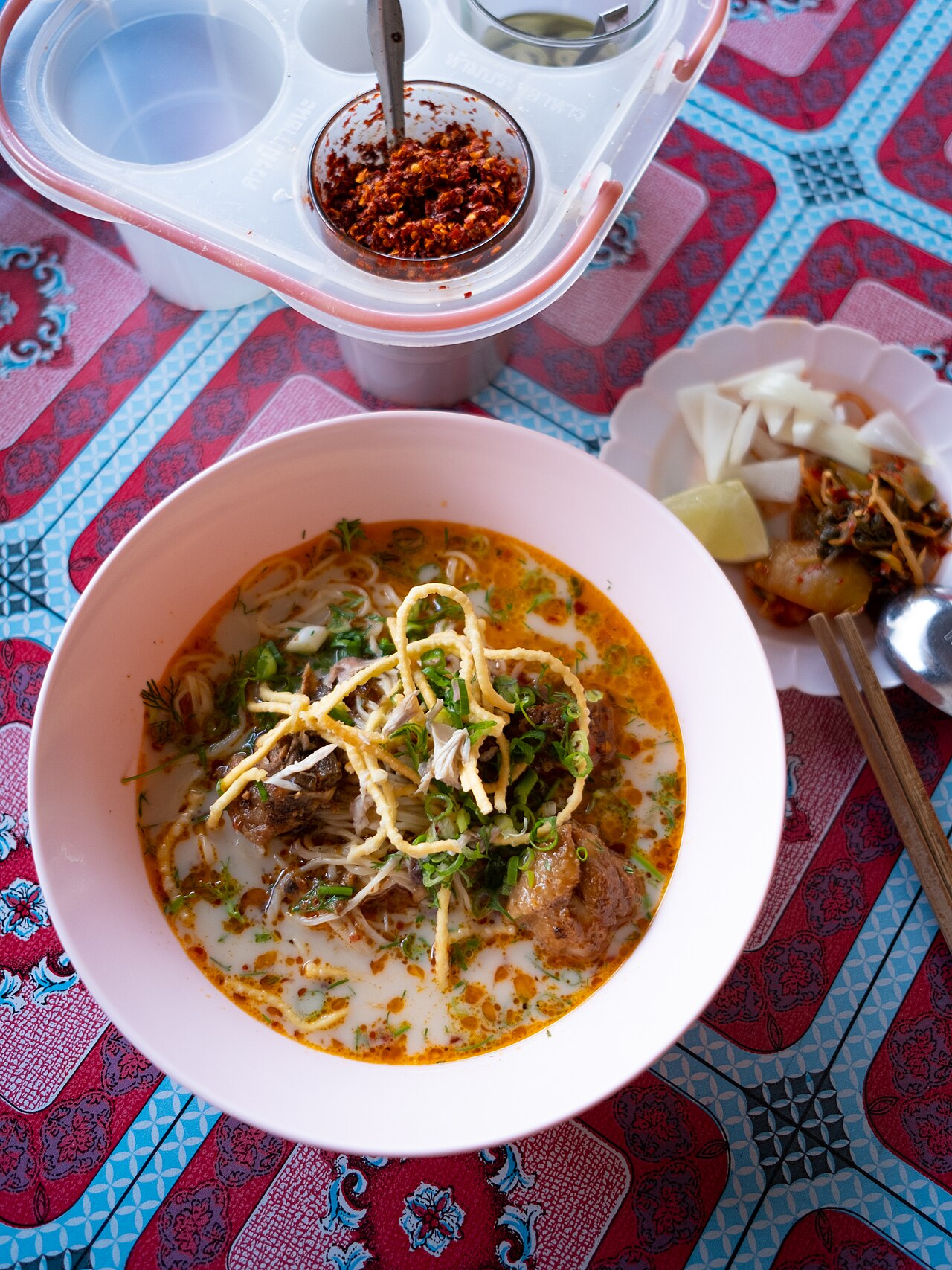 ข้าวซอยเชียงใหม่ — เส้นบะหมี่ในน้ำแกงกะทิเหลืองข้น โรยเส้นทอดกรอบ เสิร์ฟกับหอมดองและมะนาว