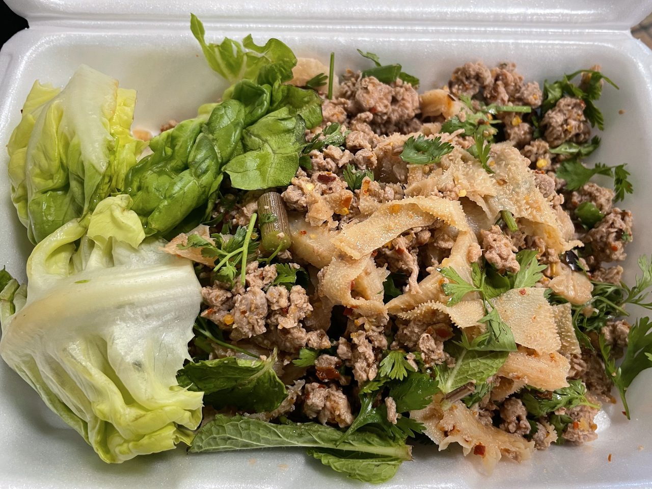 ลาบเมืองหมูจานหนึ่ง เนื้อหมูสับคลุกเครื่องเทศคั่ว โรยผักชีและสะระแหน่ เสิร์ฟคู่ผักกาดและแคบหมู