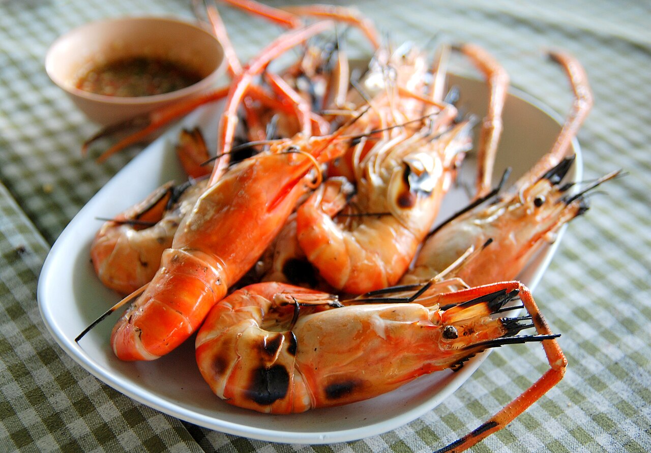 กุ้งเผาตัวโตวางบนจาน เสิร์ฟพร้อมน้ำจิ้มซีฟู้ด — เมนูซีฟู้ดยอดนิยมริมหาดอ่าวนาง กระบี่