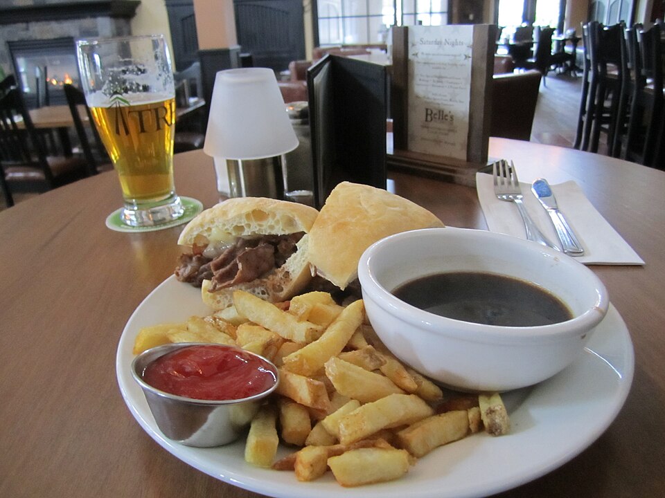 French dip sandwich of thin-sliced beef on a roll with a cup of au jus for dipping
