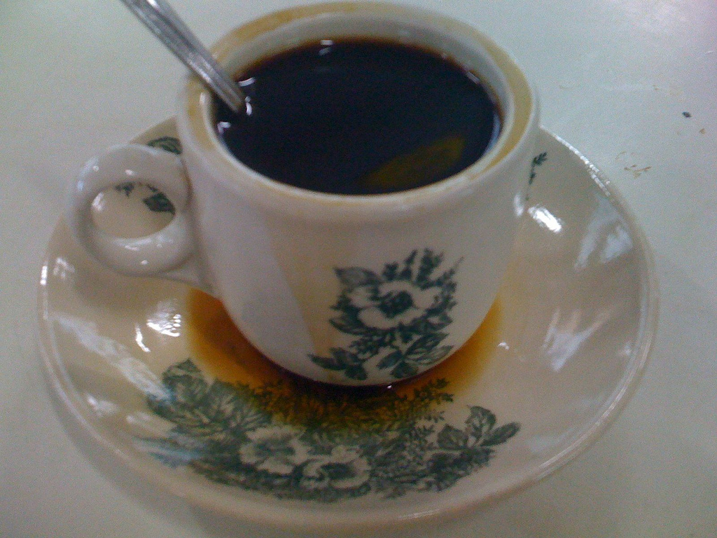 กาแฟโกปี๊ดำในถ้วยกระเบื้องลายดอกแบบร้านกาแฟโบราณ วางบนจานรอง
