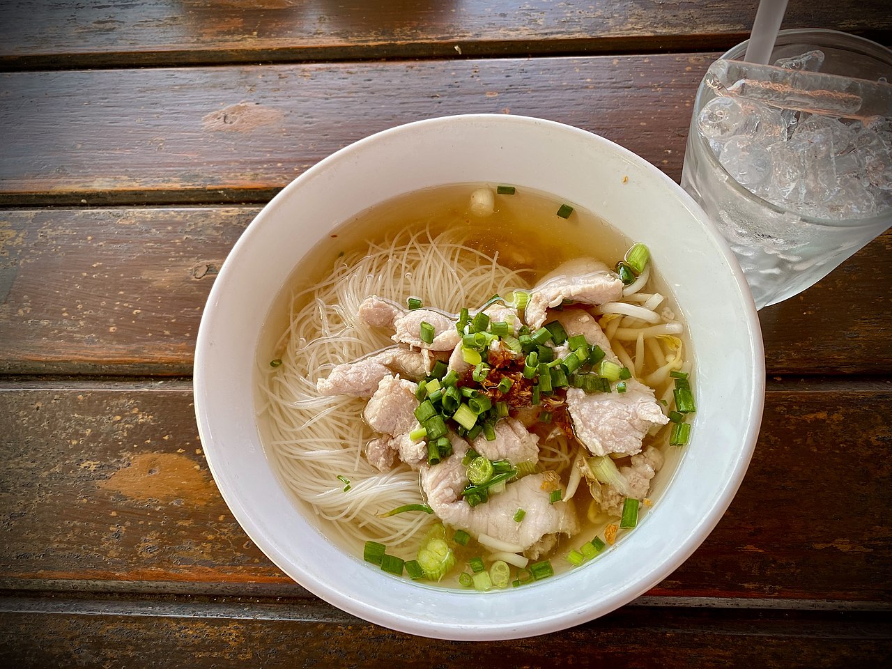 ก๋วยเตี๋ยวหมูน้ำใสชามหนึ่งในภูเก็ต โรยต้นหอมซอยและกระเทียมเจียว ตัวอย่างเมนูเส้นแบบไทยที่หากินง่ายทั่วเกาะ