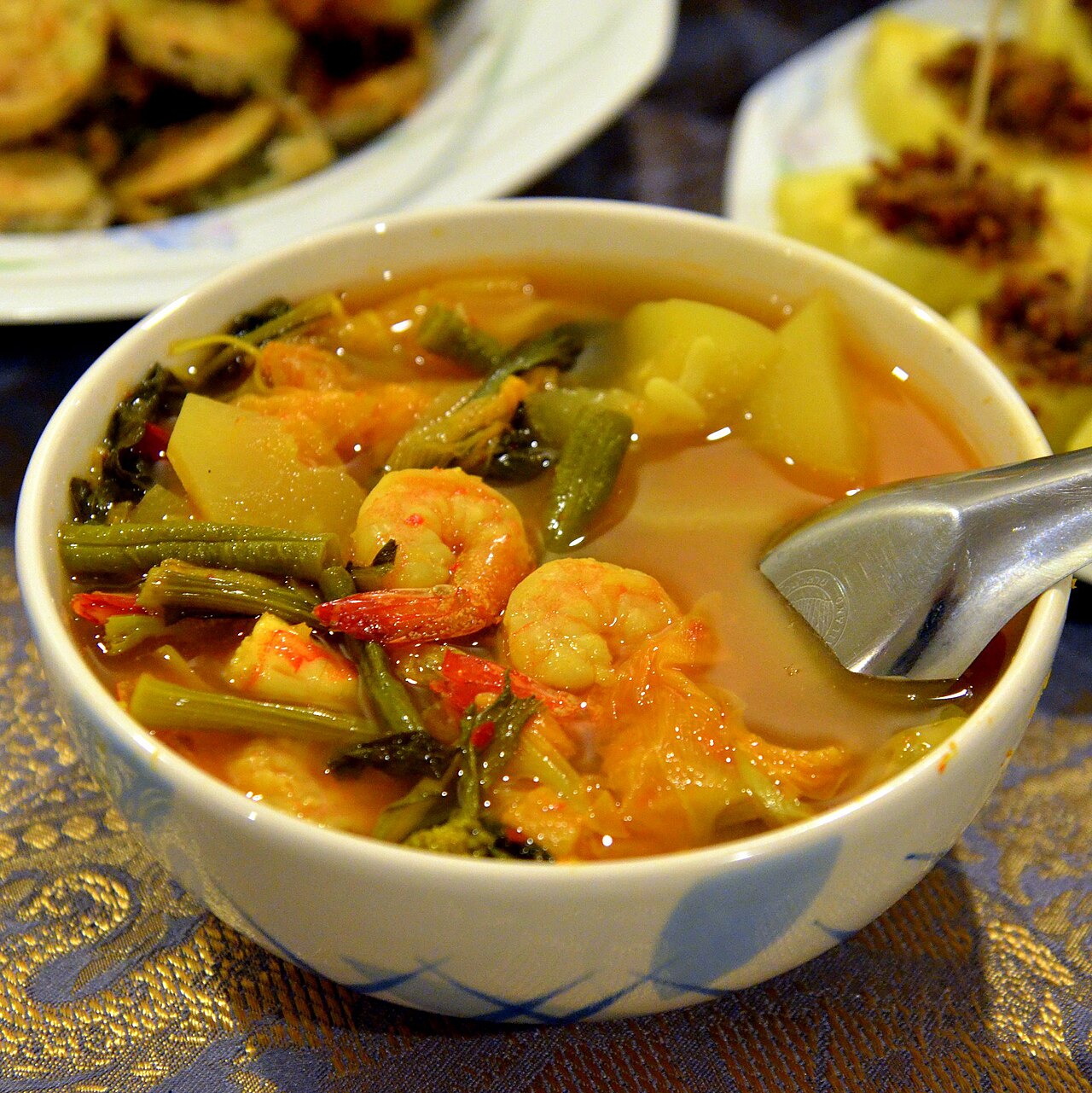แกงส้มกุ้งแบบปักษ์ใต้ในถ้วย น้ำแกงขมิ้นสีส้มเข้มใส่ผักและกุ้งตัวโต