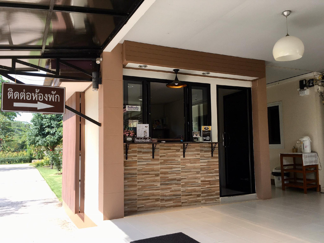 เคาน์เตอร์ต้อนรับของ Baan Ing Daan มีป้ายติดต่อห้องพักและซุ้มไม้