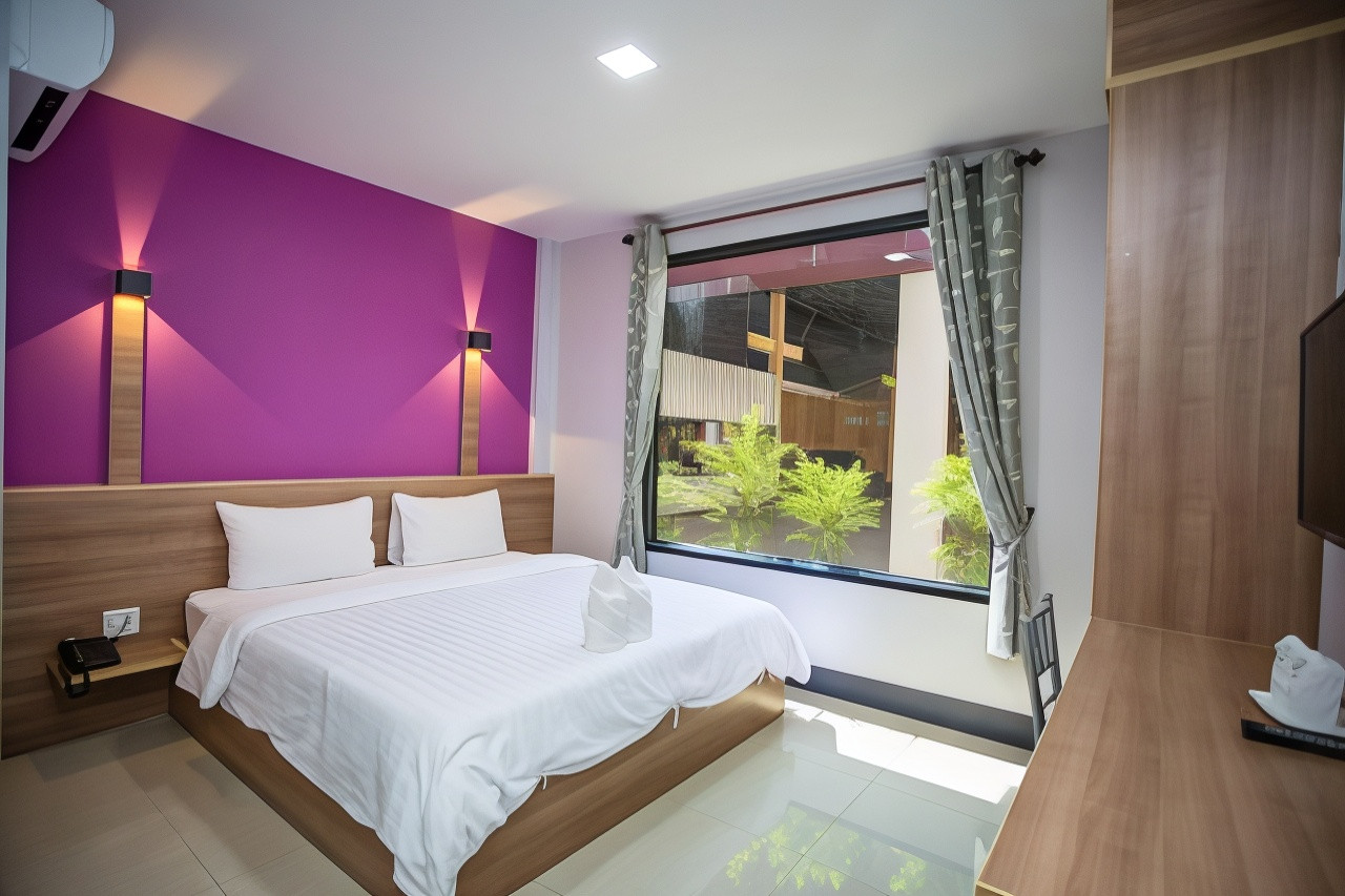 ห้องเตียงใหญ่ผนังสีม่วง หน้าต่างบานใหญ่มองออกสวนที่โรงแรมนครินทร์