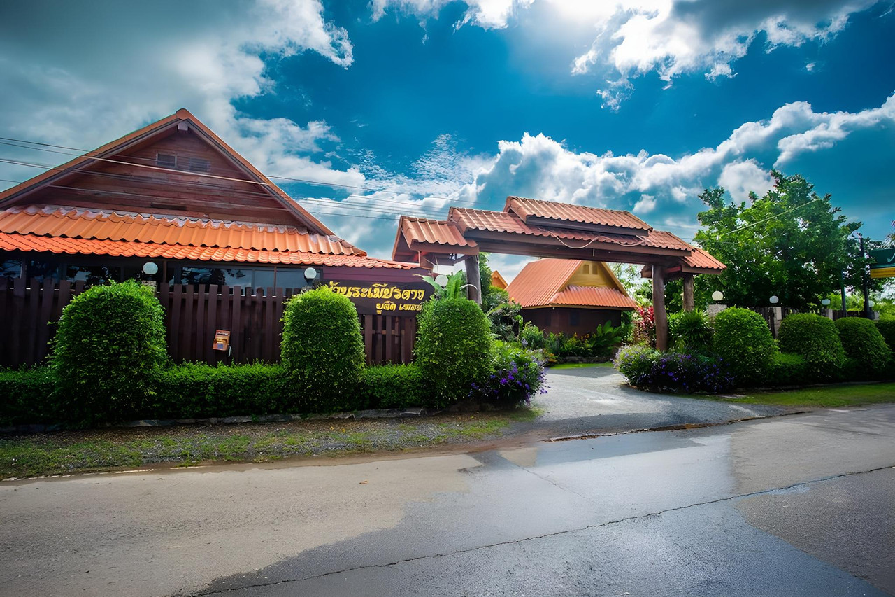 บ้านไม้หลังคาสีส้มเรียงรายในสวนริมถนน ของ Ramiarndao Boutique Place