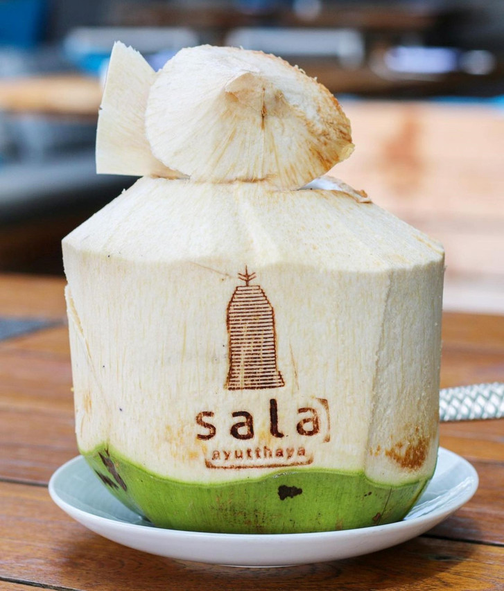มะพร้าวสดสลักโลโก้ sala ayutthaya ที่ร้านริมน้ำ