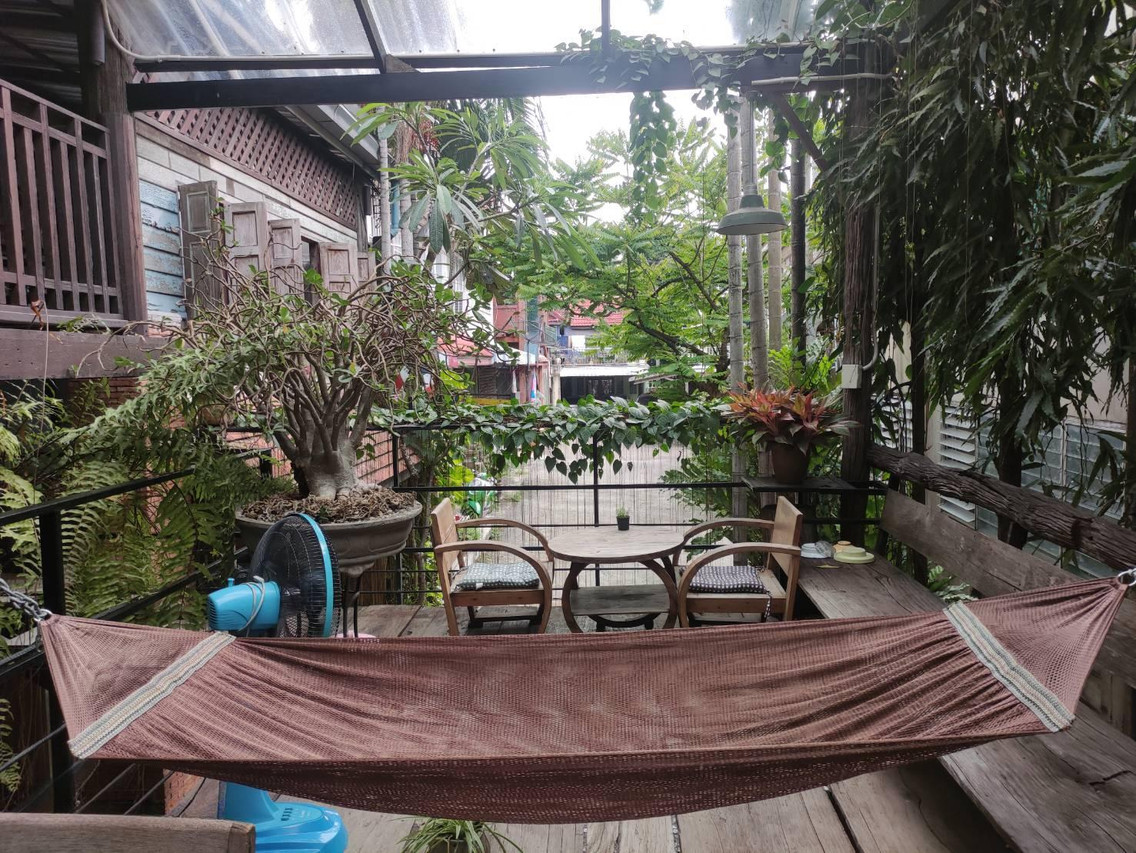 ระเบียงไม้ส่วนกลางมีบอนไซ เปลญวน และโต๊ะไม้ ของ Tamarind Guesthouse