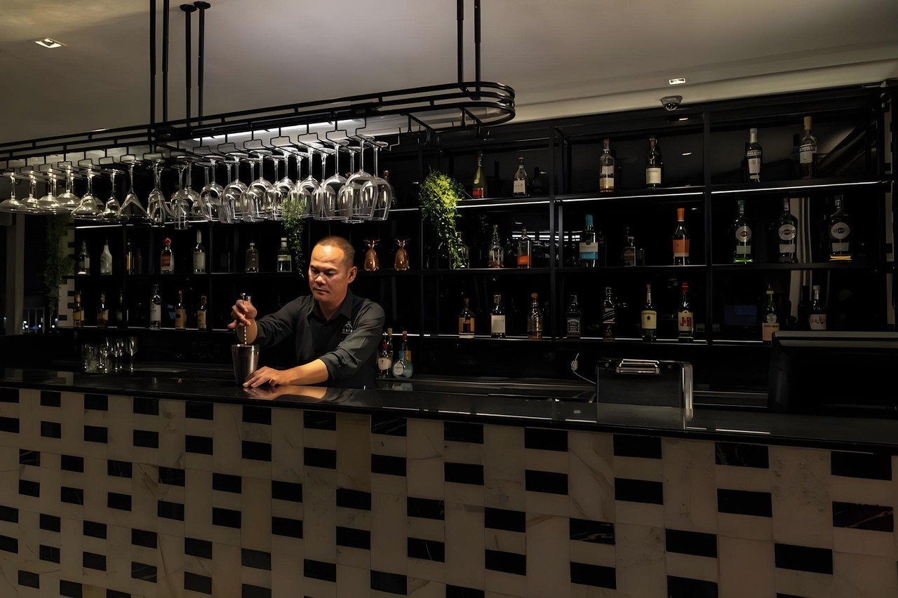 Ground-floor cocktail bar with marble brick-pattern counter and bottle shelving