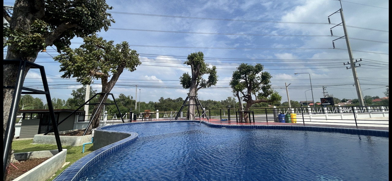 สระว่ายน้ำกลางแจ้งทรงโค้งของ Na Care Hotel ชัยภูมิ พร้อมต้นไม้จัดสวน