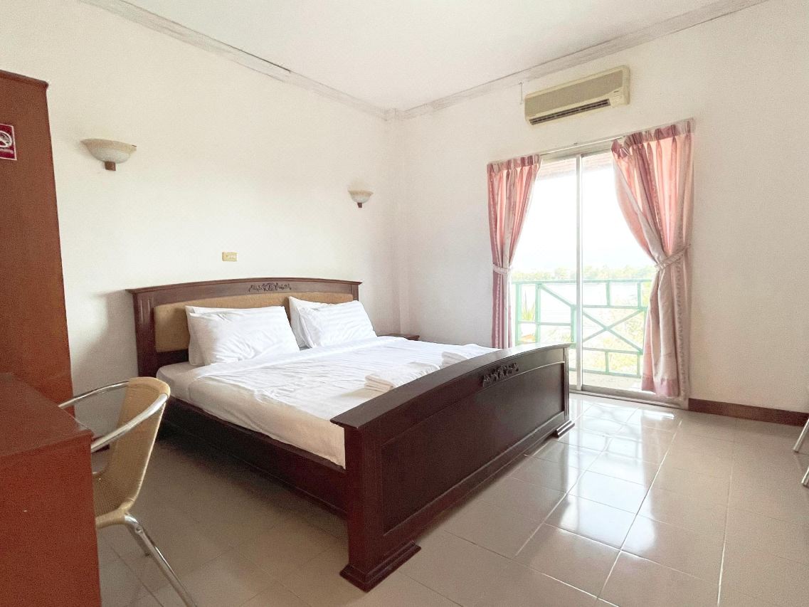 ห้องนอนเตียงคู่ไม้สีน้ำตาล มีระเบียงและแอร์ ที่ Phusuay Namsai Resort ภูเขียว