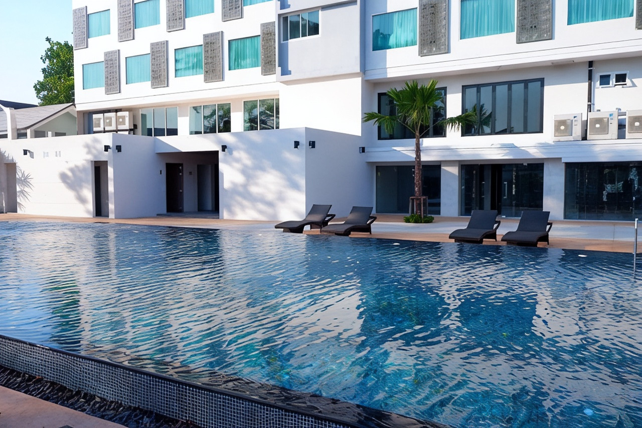 สระว่ายน้ำกลางแจ้งของ Sann Hotel Chiang Rai กับเก้าอี้อาบแดดและต้นปาล์ม