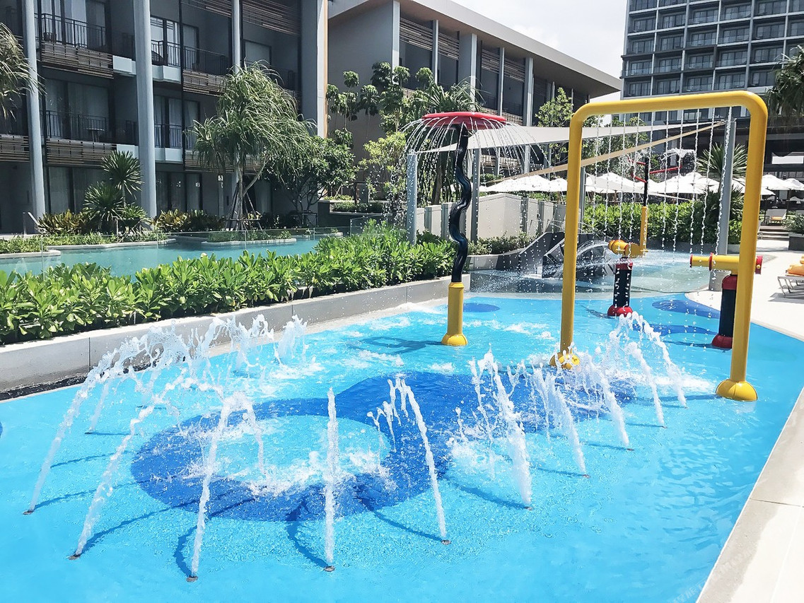 โซนสระเด็กแบบ splash pool กับอาคารห้องพักรอบสระ