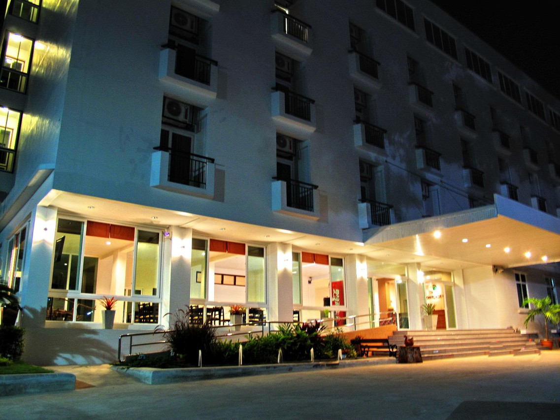ภาพตึกขาวของ Phaiboon Place Hotel ยามค่ำ ทางเข้ามีไฟส่องสว่าง