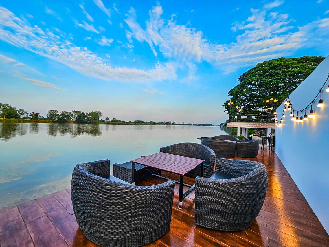 เด็คไม้ริมแม่น้ำปิง เก้าอี้หวายกับโต๊ะ มองข้ามน้ำตอนเย็น ที่ Mango House Resort