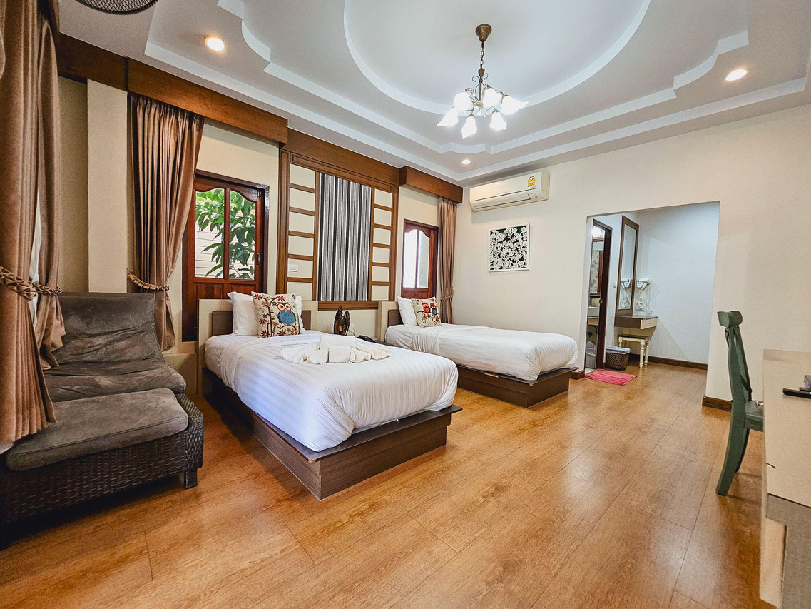 ห้องพักในบังกะโลไม้ พื้นไม้ เตียงแฝด แต่งทรงไทยร่วมสมัย