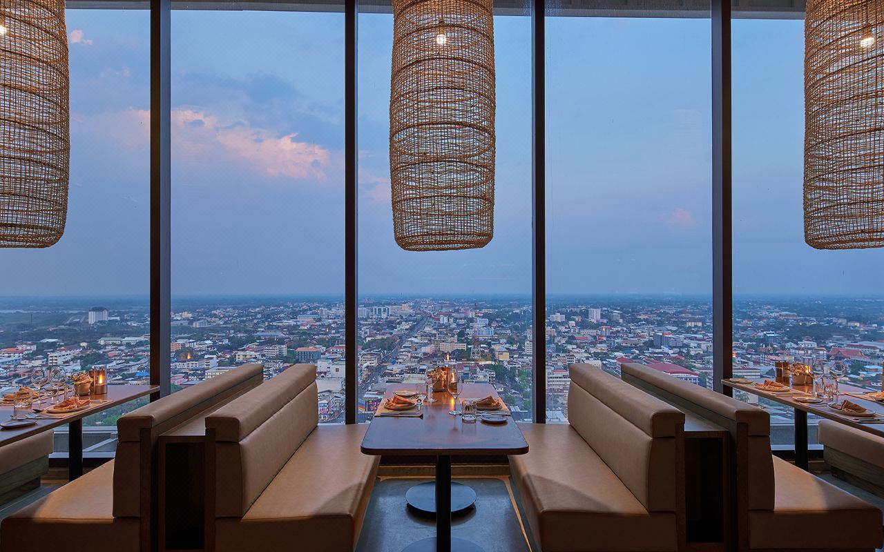 Upper-floor restaurant with rattan pendant lamps and a panoramic Khon Kaen city view