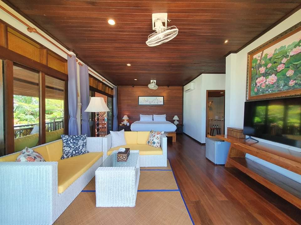 Beachfront villa interior with teak floors, rattan sofas and a sea-facing veranda