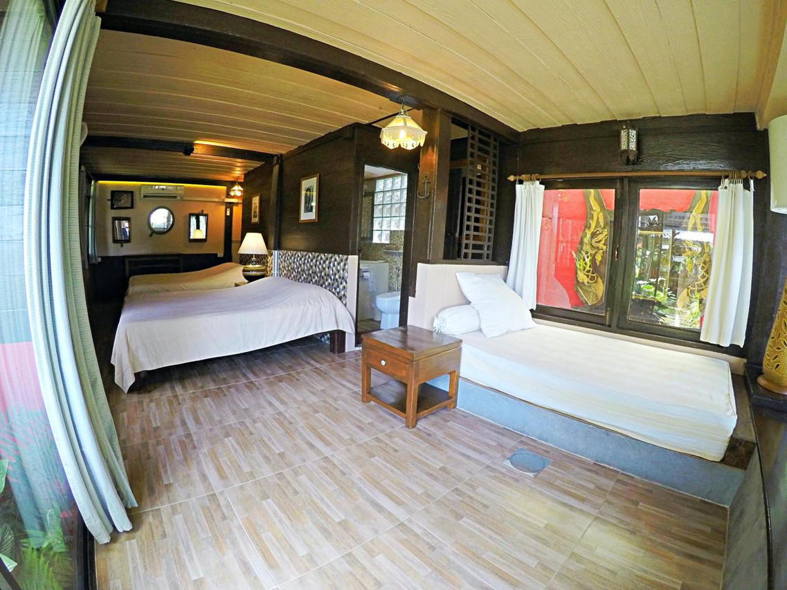 ห้องพักเรือนไม้สัก เตียงคู่และห้องน้ำในตัว The Riverside Guest House ลำปาง