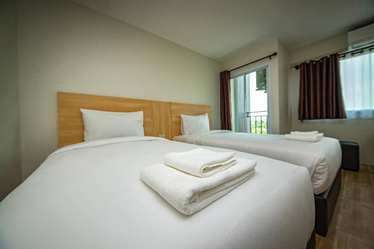 ห้อง Twin พร้อมประตูระเบียง ผ้าเช็ดตัวพับวางบนเตียง The Charlotte Smart Hotel Lopburi