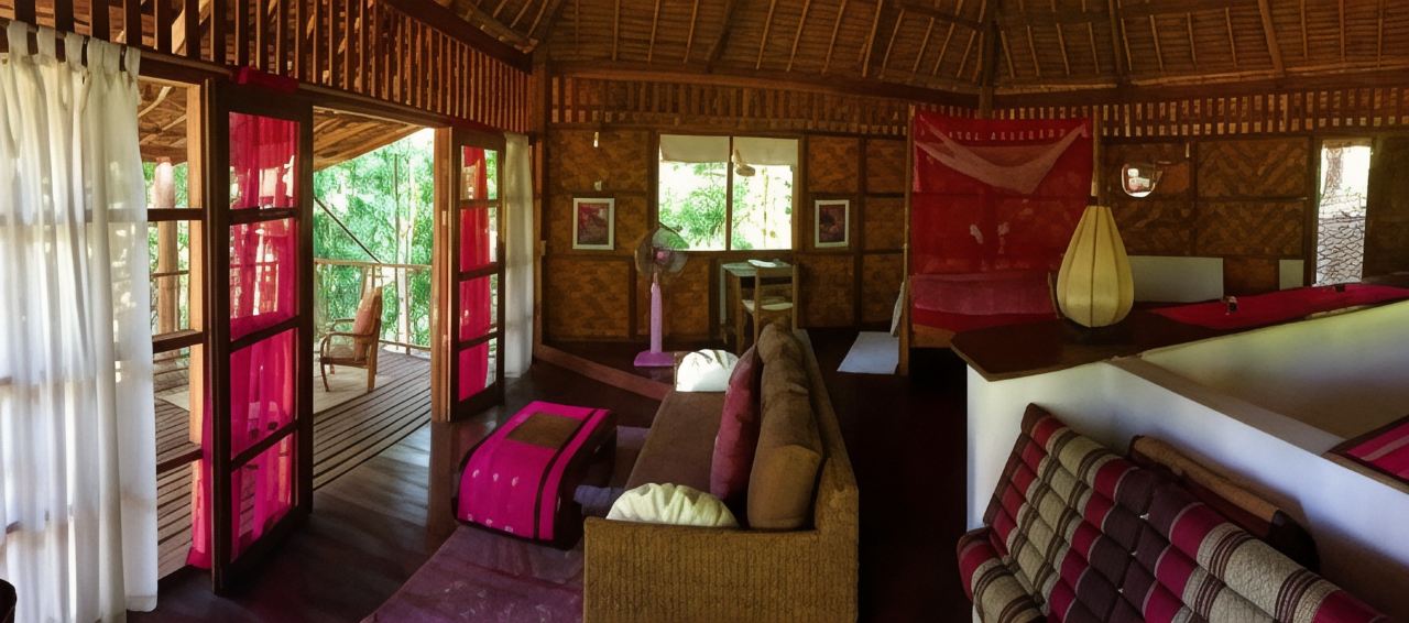Interior of a teak-and-bamboo hut at Sang Tong Huts opening onto a garden balcony