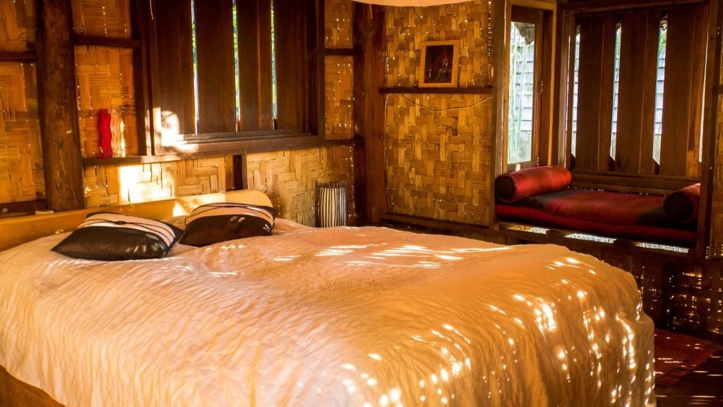 Hut bedroom with a comfortable bed, woven bamboo walls and light through the windows