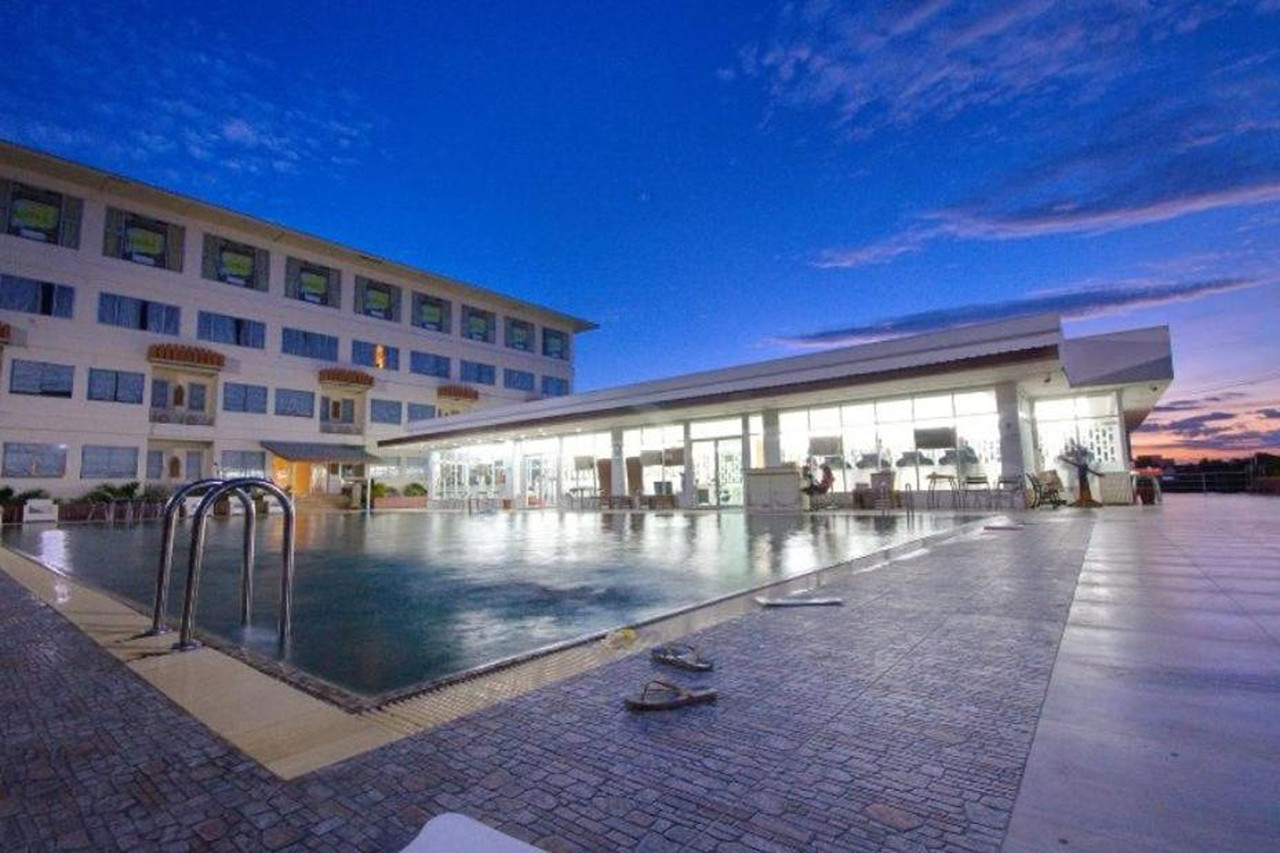 สระว่ายน้ำกลางแจ้งของ Taksila Hotel ยามเย็น มีอาคารห้องพักอยู่ด้านหลัง