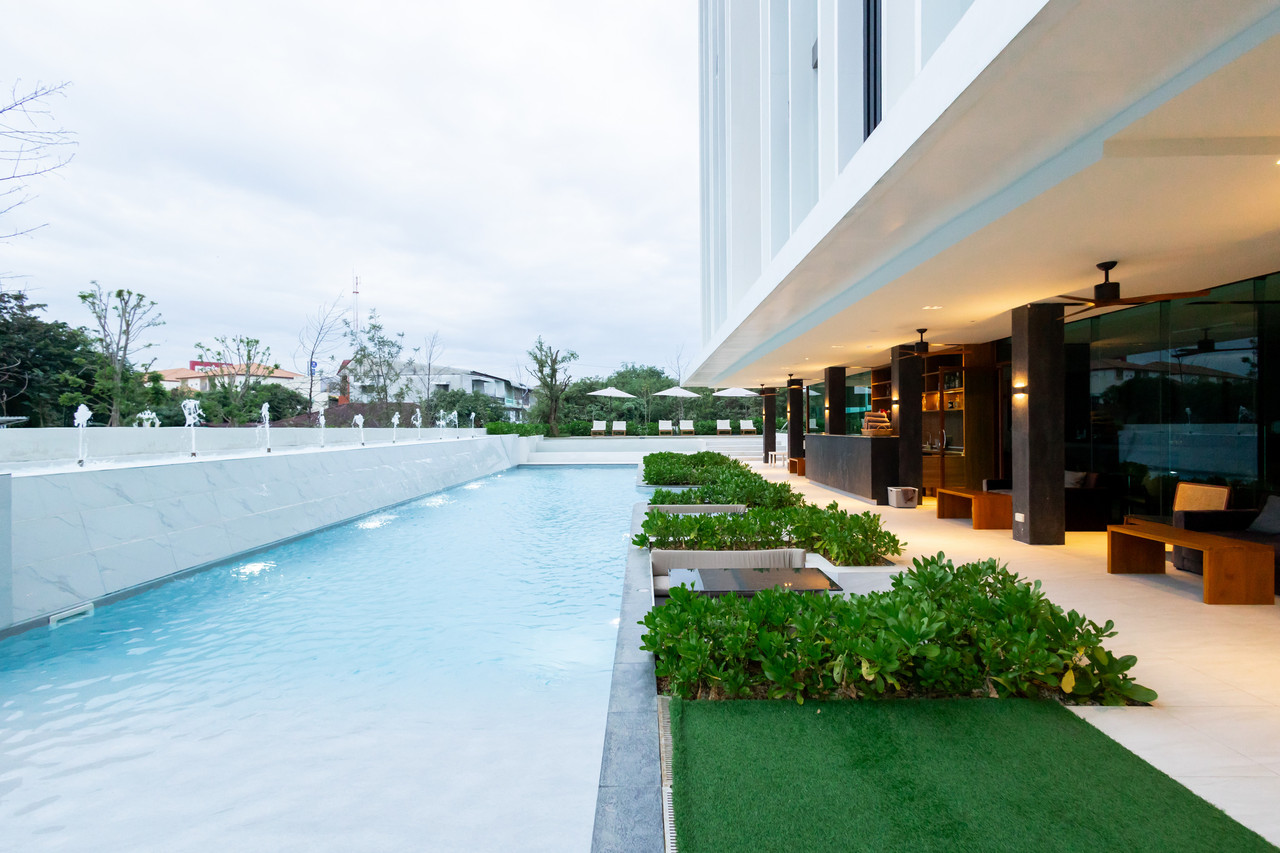 สระว่ายน้ำกลางแจ้งติดน้ำพุ ขนาบด้วยตึกสีขาวและสวนหญ้าเขียว GOOD Nakhonsawan Hotel