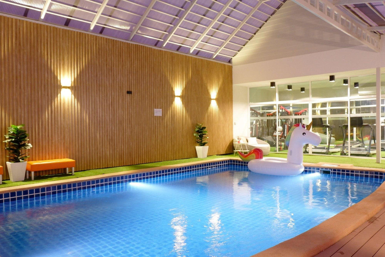 สระว่ายน้ำในร่มหลังคาโปร่ง มีมุมฟิตเนสหลังกระจก Grand Hill Resort and Spa