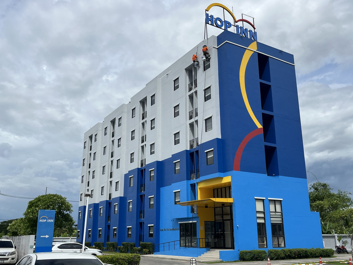 อาคารด้านนอก Hop Inn Nakhon Si Thammarat สีน้ำเงิน-ขาว พร้อมป้ายบนดาดฟ้า