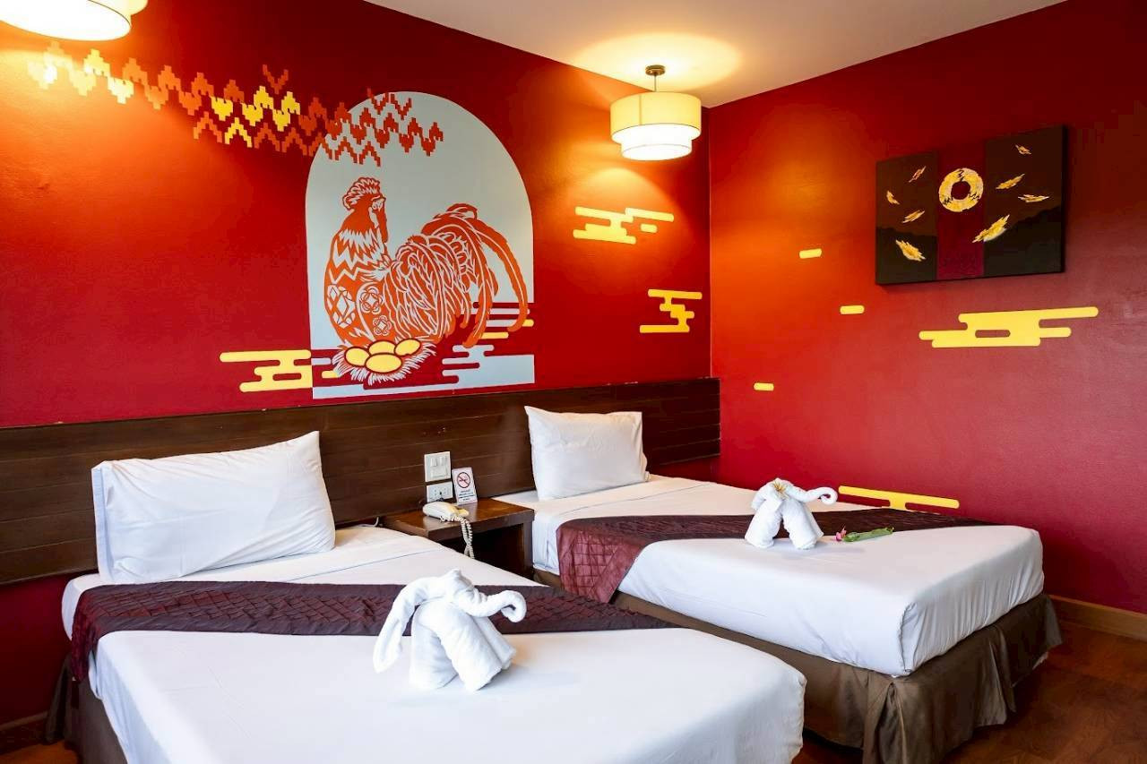 ห้อง Superior Twin ผนังแดงพร้อมภาพวาดลายไก่และลายเมฆไทยที่ The Ligor City Hotel