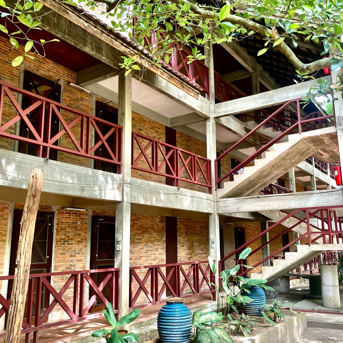 Brick room block with red-painted wooden balconies around the garden