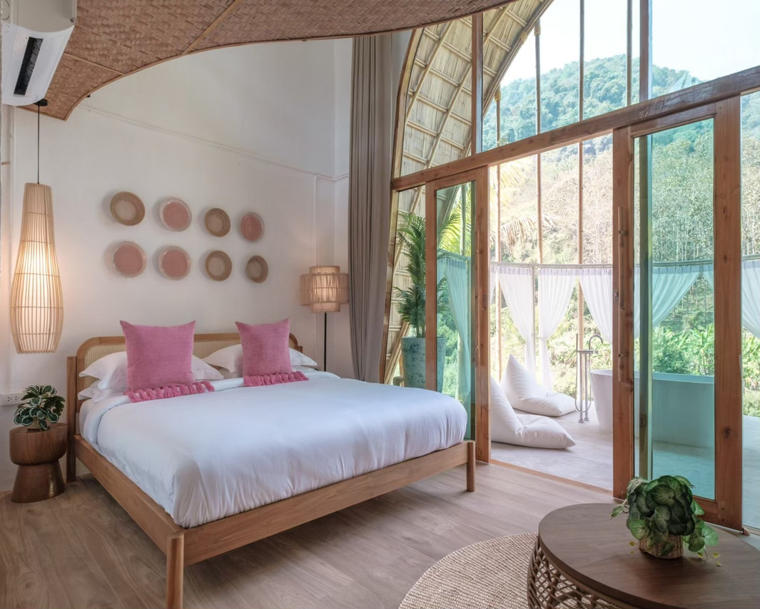ห้องวิลล่าหลังคาโค้งไม้ไผ่ ผนังโทนขาว วิวภูเขาผ่านกระจกบานใหญ่ที่ Phu Ka Na Nan Resort