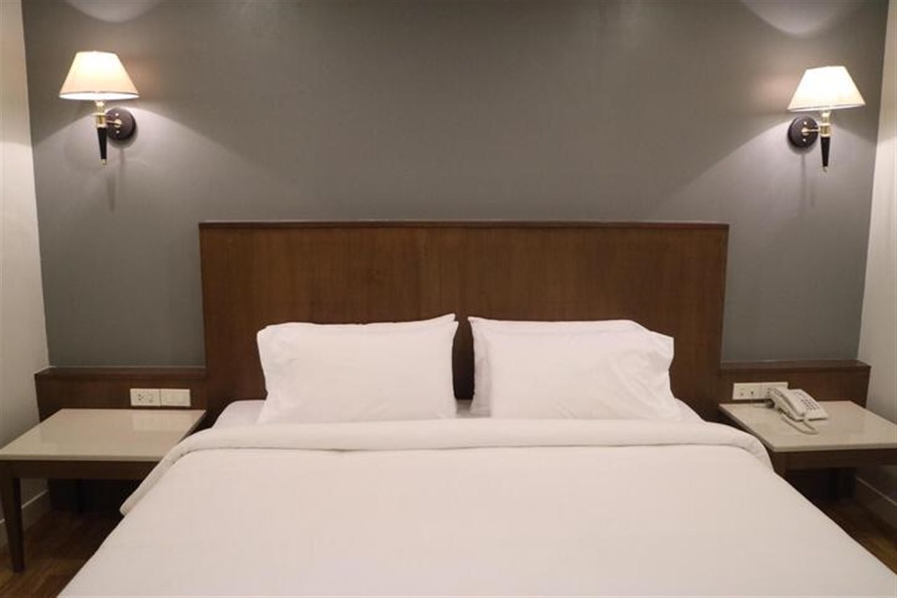 ห้องพัก Grand Garden Hotel เตียงใหญ่ หัวเตียงไม้ โคมไฟข้างเตียงคู่