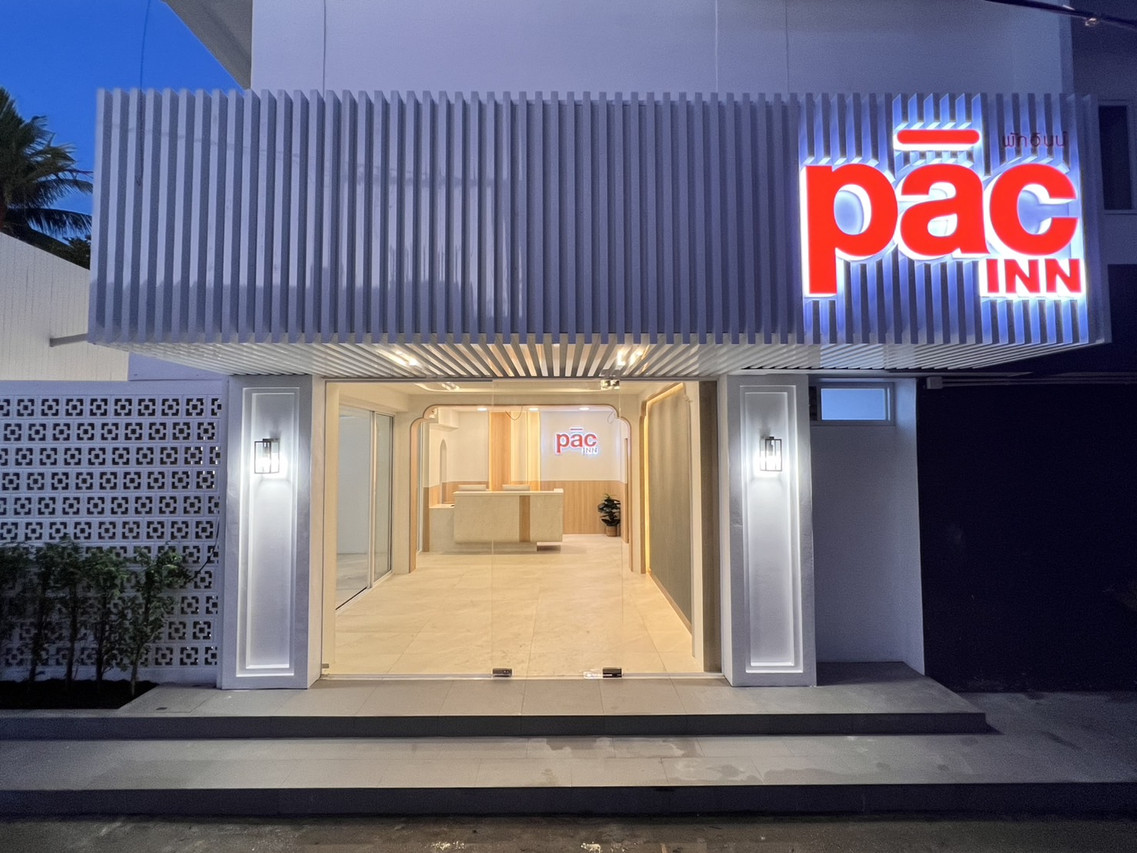 หน้าตึก Pacinn Narathiwat ช่วงค่ำ ป้าย pāc INN สีแดงเปิดไฟ ทางเข้ากระจกเห็นล็อบบี้