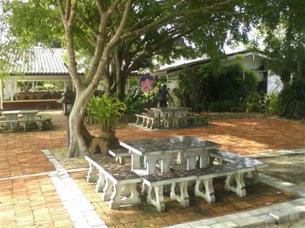 สวนกว้างกลางรีสอร์ท มีต้นไม้ใหญ่และโต๊ะหินสำหรับนั่งเล่น