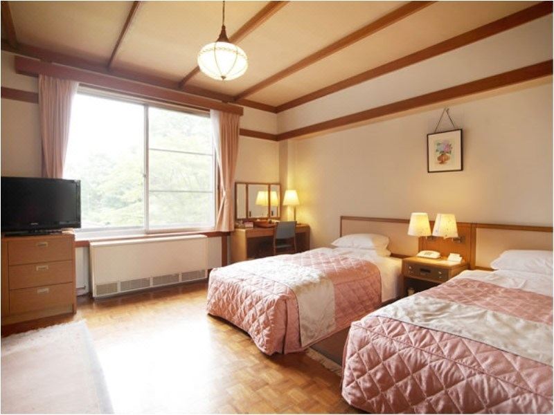 ห้องพัก Twin ของ Nikko Kanaya Hotel พื้นไม้ parquet โคมไฟยุคเก่าและวิวสวน