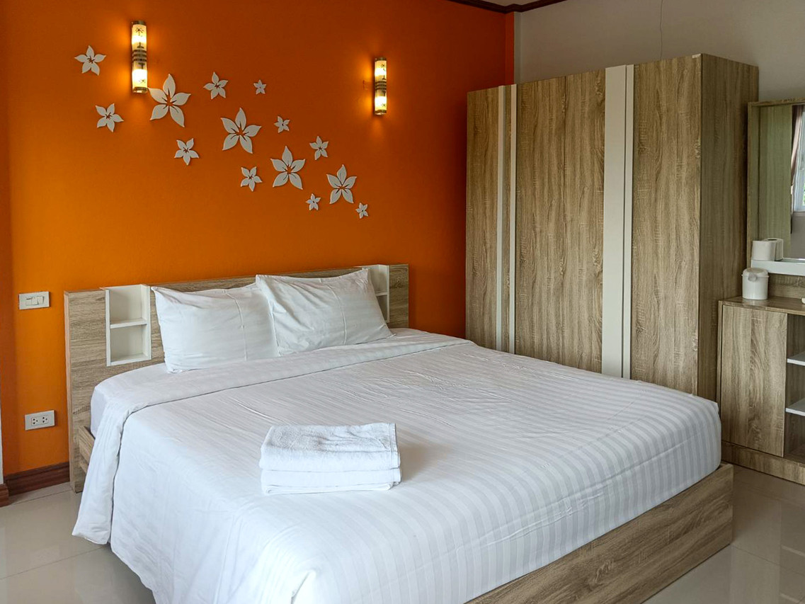 ห้อง Standard Double ผนังสีส้ม เตียงใหญ่ ตู้เสื้อผ้าไม้ ที่ Rueanchorfa Hotel