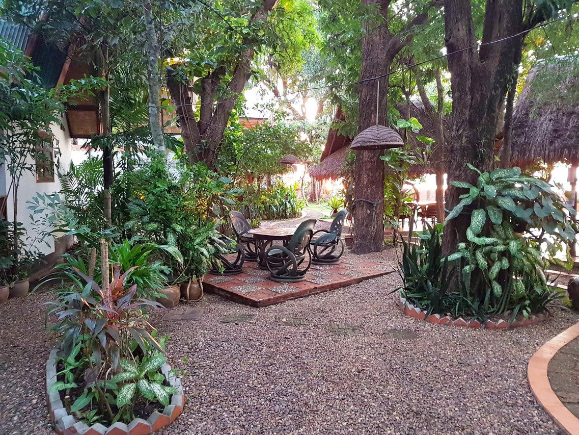 สวนร่มไม้ใหญ่พร้อมโต๊ะนั่งเล่นใน Mut Mee Garden Guesthouse