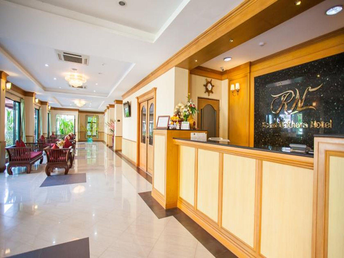 ล็อบบี้และเคาน์เตอร์ต้อนรับของ Royal Nakhara Hotel มีโลโก้ RN บนผนัง