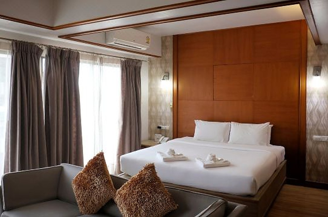 ห้อง Deluxe ของ Nonthaburi Palace Hotel เตียงใหญ่ ผนังไม้ มีระเบียง
