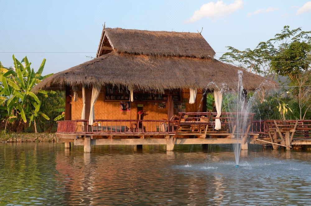 Thatched wooden sala over the pond with a fountain at Bueng Pai Farm