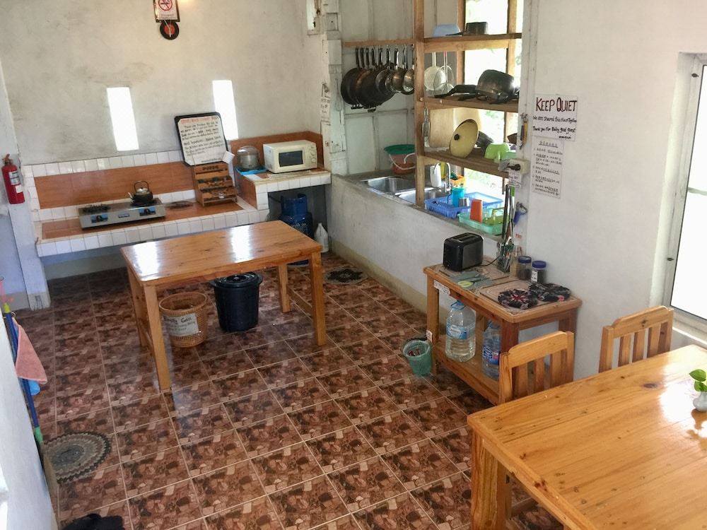 Shared guest kitchen with stove, microwave and wooden tables for self-catering
